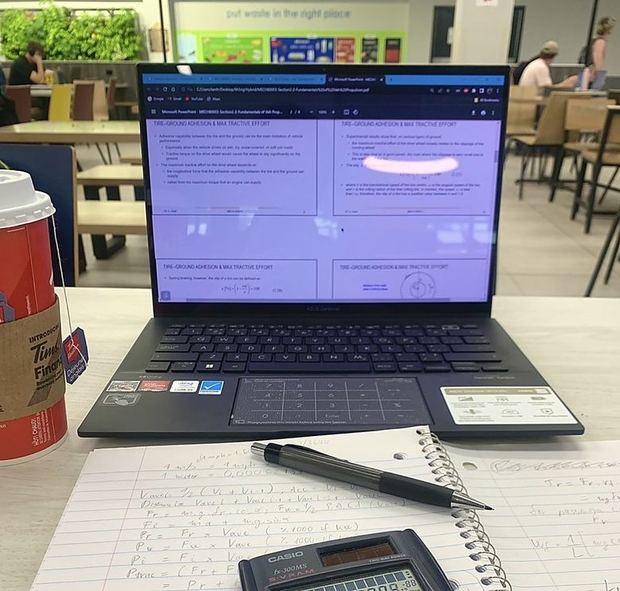 Laptop và vở ghi trên bàn.